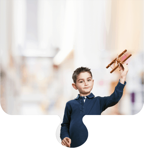 Jongen met speelgoed vliegtuig wijst naar de camera.